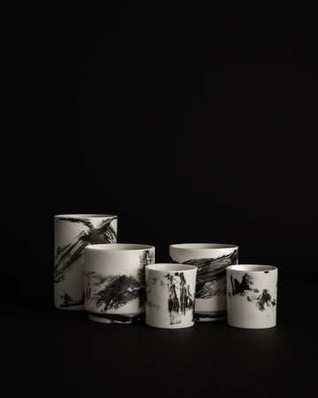 Kilka ręcznie malowanych naczyń DaDa z porcelany Parian na czarnym tle, każde z innym układem czarnych linii